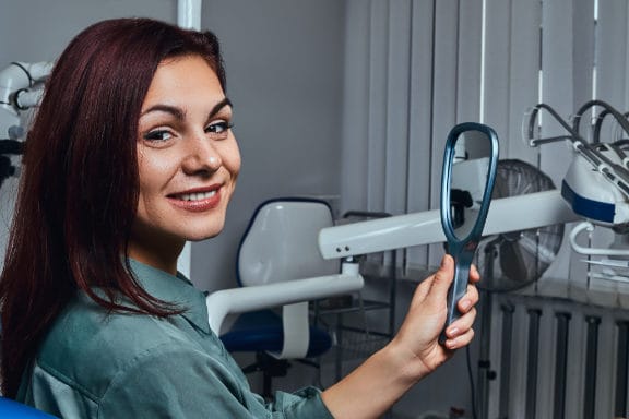 Woman in dental chair looking at a mirror