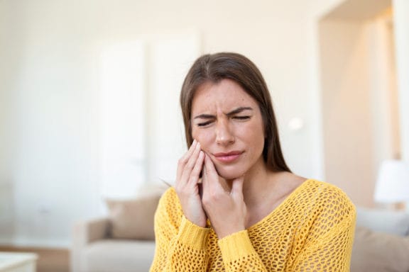 Woman holding her cheek in pain